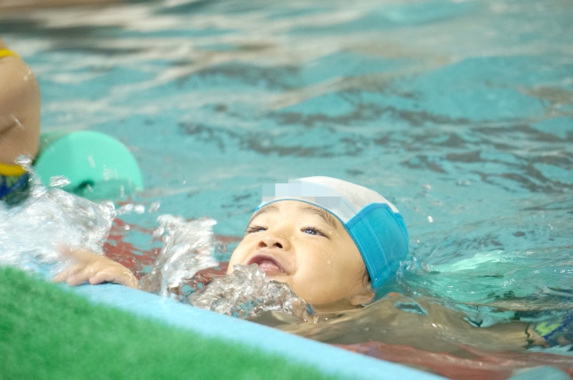 スイミングプールで泳ぐ男の子の写真