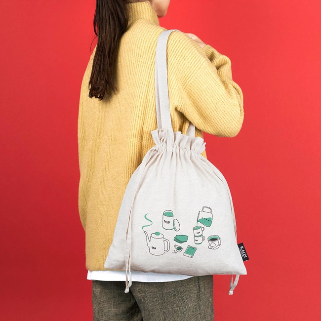 カルディ福袋2024　ドリップコーヒーセットのバッグを女性が肩にかけている写真